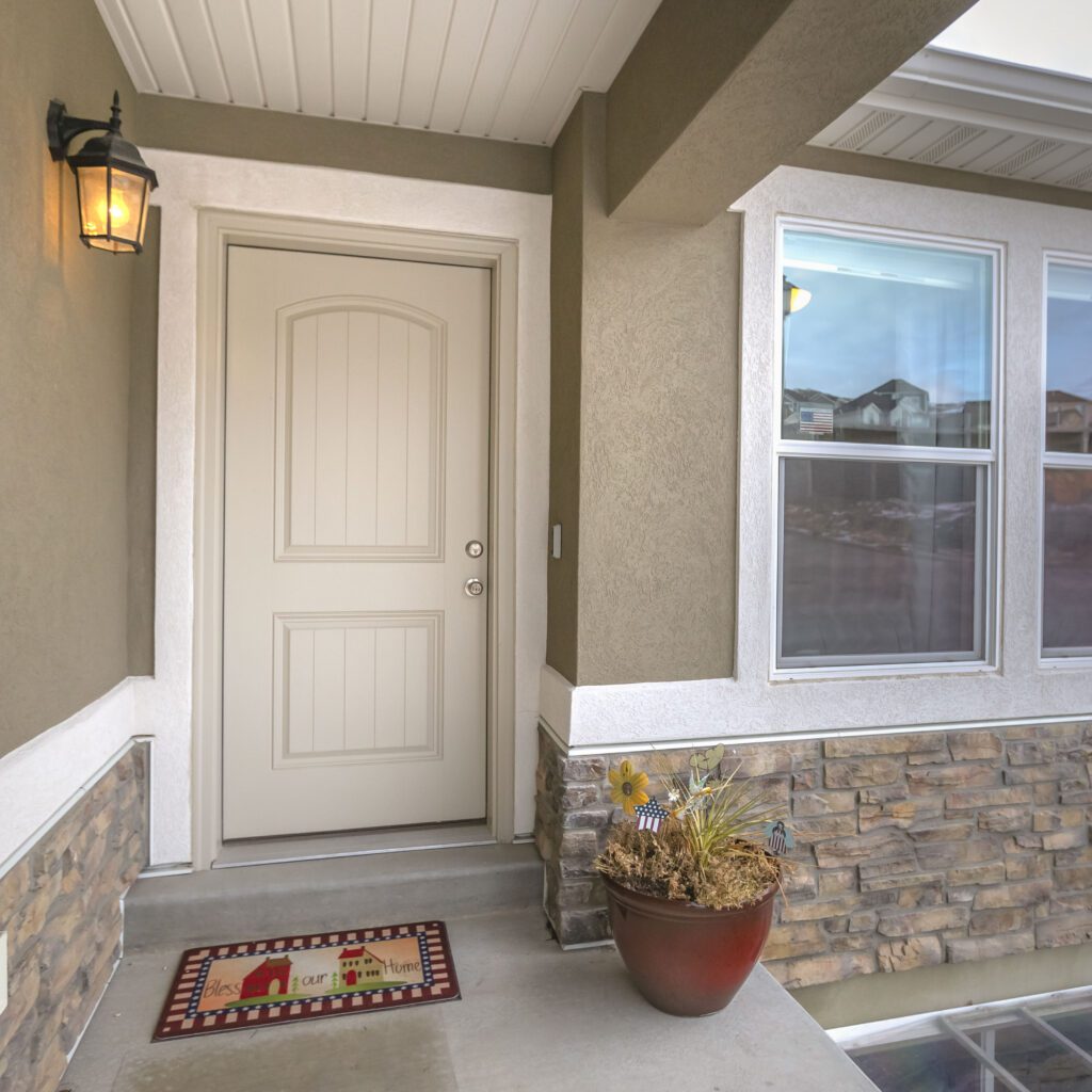 Square White front door and reflective window of a home against road and cloudy sky